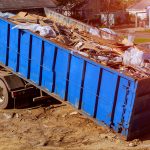 Blue construction debris container filled with rock and concrete rubble. Industrial garbage bin
